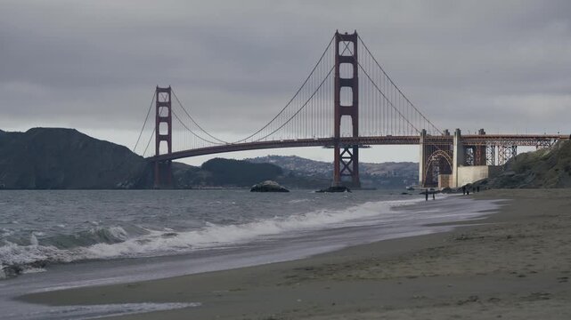 Walker And Jogger On Beach Near Golden Gate Bridge In San Francisco - Wide Shot