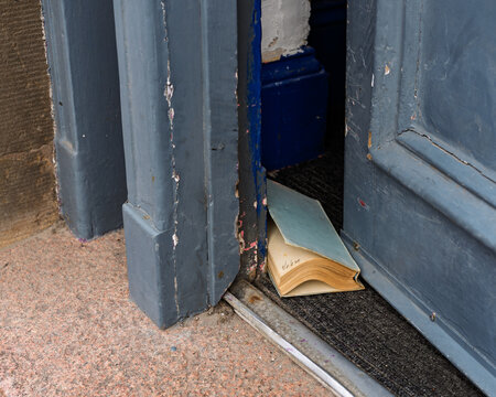 Worn old book preventing a door from closing in Buckie, Moray, Scotland