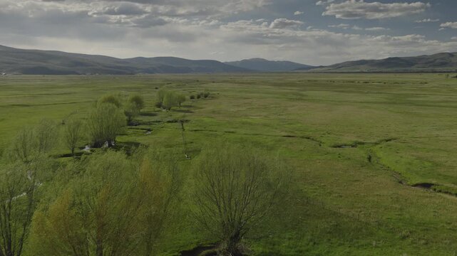 An aerial flyover of a stream running through marshland and meadows, Kamas, Utah