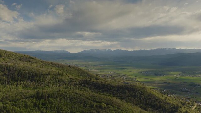 An aerial flyover of foothills near the Uintah mountains revealing a valley and farmland in the distance, Kamas, Utah