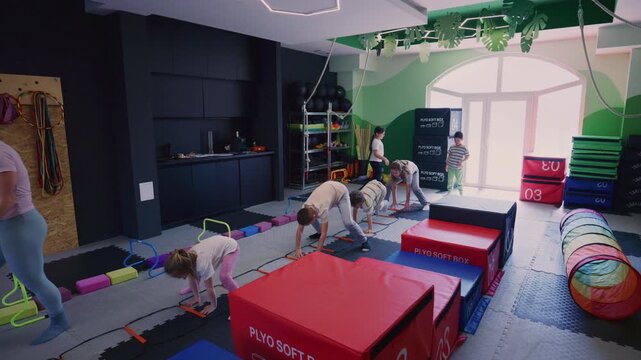 Children engage in a vibrant fitness training session, guided by an instructor. They perform various exercises and overcome obstacles in a colorful gym.