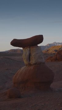 An aerial flyby vertical video of a sandstone hoodoo at sunrise, Little Egypt, Utah