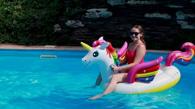 Woman on inflatable unicorn pool float in pool in hotel. Summer holidays, enjoying summer vacations 
