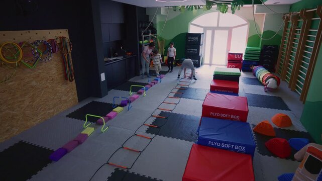 Children participate in a dynamic fitness obstacle course, developing motor skills and balance. Youngsters engage in active play and physical training in a vibrant gym environment.