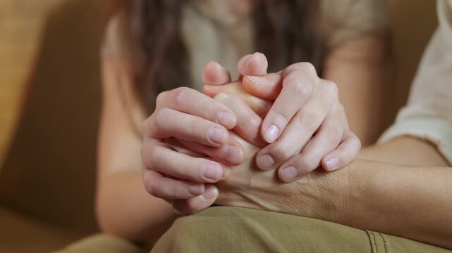 Caring daughter holding worried mother's hands. Supportive grown daughter comforting her senior mother, gently stroking her hands to give solace and empathy during a difficult time, showing