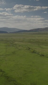 An aerial flyover vertical video of marshland and meadows near rural farms, Kamas, Utah