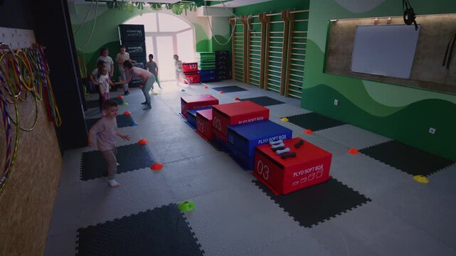 Young children actively participate in a fun fitness class with an instructor. Kids enjoy playful exercises and movement in a stimulating gym environment.