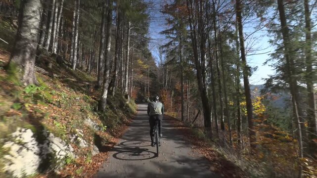Rear view of a cyclist on a gravel bike climbing towards Schwarzenkopf peak near Spitzingsee. A scenic autumn ascent in the Mangfallgebirge, Bavarian Prealps, during a sunny day in Upper Bavaria