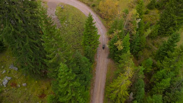Drohnenaufnahme eines Radfahrers, der sein Gravelbike zum Soinsee hochschiebt. Herbstliche Bergtour bei Bayrischzell im Mangfallgebirge, Bayerische Voralpen, waehrend der Nebel die Gipfel einhuellt