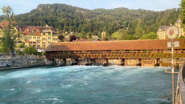 Historic wooden sluice bridge with flower decorations over rushing Aare river in Thun Switzerland