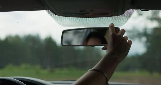 Young woman driver regulating rear view mirror before starting a road trip