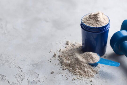 Protein powder in a blue container with a scoop and dumbbell on a light background. Sports nutrition supplement for fitness and bodybuilding. Top view with copy space
