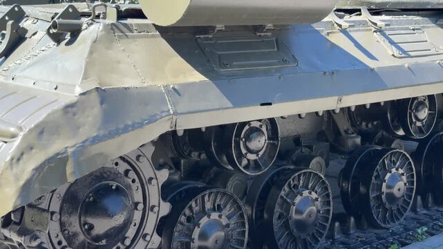 Military Tank Track Detail: A close-up view of the rugged metal tracks and heavy wheels of a military combat vehicle, highlighting the engineering and durable structure of armor equipment.