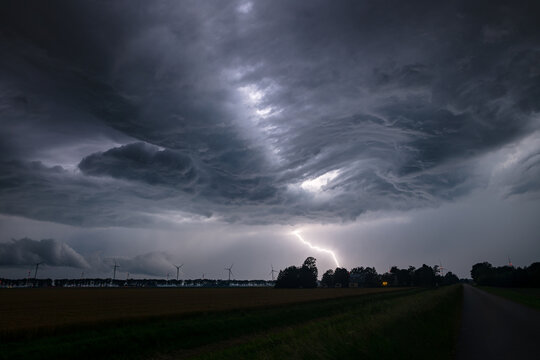 Dramatic lightning strike under dark supercell storm clouds over rural farmland in Flevoland, Netherlands