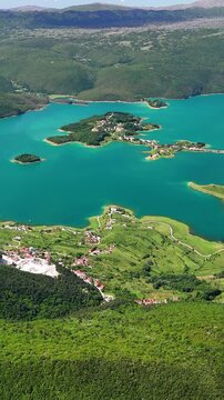 Vertical aerial view of Rama Lake, a beautiful and breathtaking lake with many small islands. It is truly a stunning sight, surrounded by lush green mountain slopes. Bosnia and Herzegovina.	
