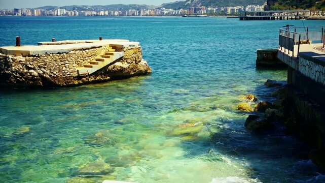 Old Stone Pier With Concrete Steps In Clear Turquoise Sea Water Near Waterfront. Mediterranean Resort
