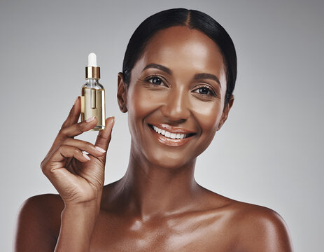 Radiant Black Woman Smiling and Holding Essential Oil Serum Bottle
