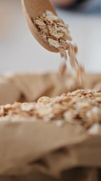 Close-up of a bag of oatmeal. A housewife stirs oatmeal with a wooden spoon. The action takes place in a home kitchen. Healthy food concept dry muesli oatmeal