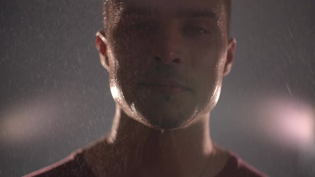 Desperate man laughing in the rain at night, crazed laughter as tension peaks, smiling through suffering.
