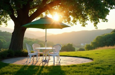 Fototapeta premium Outdoor table and chairs under tree with umbrella. Scenic landscape with hills and warm sunset light. Perfect spot for dinner or picnic on green grass.