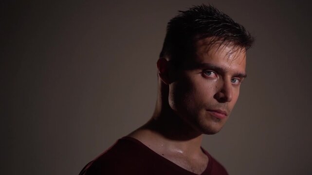 Young man calmly turning head and looking into camera with responsive, engaged expression. 
