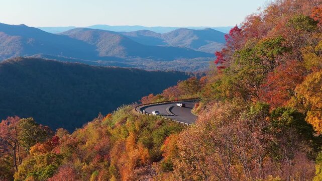 Autumn landscape in Appalachian Mountains of Tennessee featuring parked car at roadside overlook with panoramic forest views.