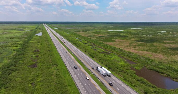 Florida freeway near Gainesville running between lush wetland areas under bright sunshine, with cars and trucks cruising along the straight road.