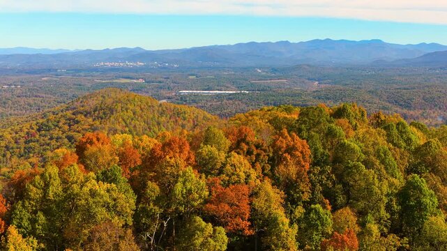 Rolling forested hills glowing with colorful autumn foliage beneath vivid sunset sky. Peaceful seasonal mountain landscape showcasing beauty of fall nature.