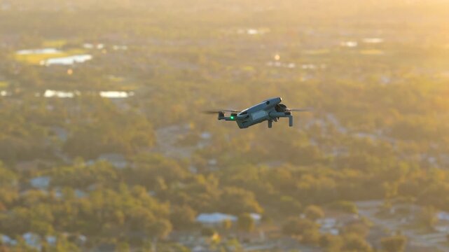 Small battery powered drone in flight above rural landscape, performing aerial survey and environmental monitoring with stabilized gimbal camera and autonomous navigation system.