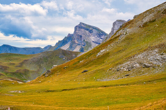 Majestic high-altitude alpine landscape featuring the rugged rocky peaks of Mount Korab with golden meadow slopes, Mavrovo National Park, Macedonia.