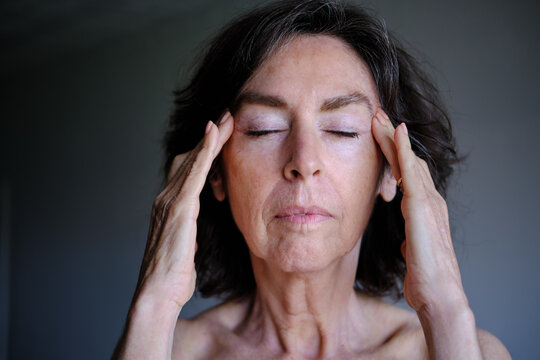 front view of Senior woman relieving stress with temple massage