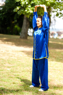 Woman practicing tai chi qigong in a blue uniform