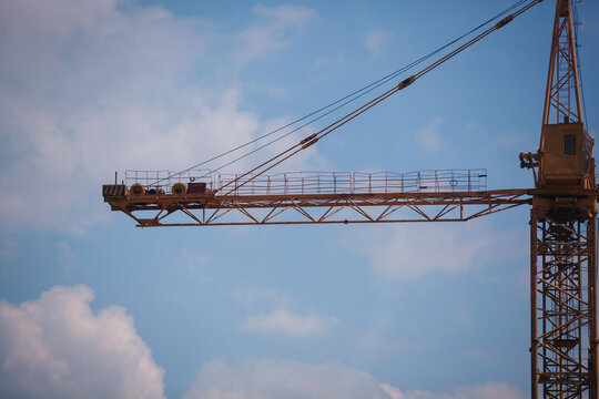 Close-up of a yellow tower crane jib end against clear blue sky with large copy space