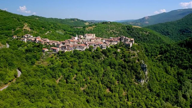 Posticciola tiny hilltop village Turano Dam Italy 4K Drone. Cinematic flight from diga reservoir revealing hilltop medieval stone borgo in green forest. Scenic orbit aerial approach video, hidden gems