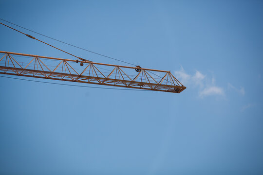 Close-up of a yellow tower crane jib end against clear blue sky with large copy space