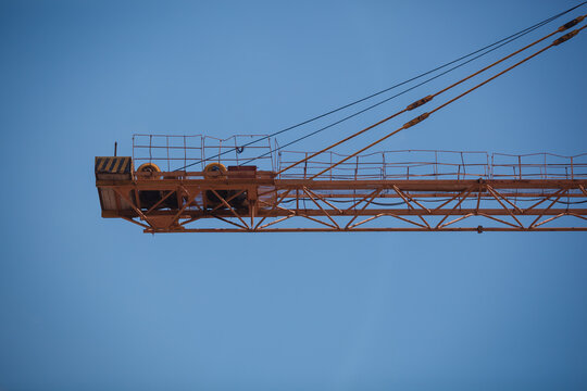 Close-up of a yellow tower crane jib end against clear blue sky with large copy space