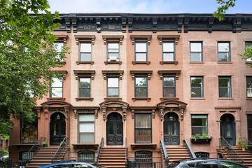 New York City, row of brownstone townhouses with ornate window frames © Spiroview Inc.