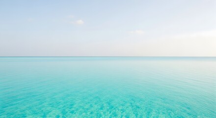 Fototapeta premium Expansive view of a tranquil turquoise ocean meeting a clear, pale blue sky at the horizon