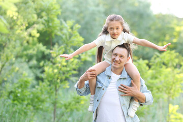 Fototapeta premium Smiling father and his daughter spending time together outdoors on sunny day. Space for text