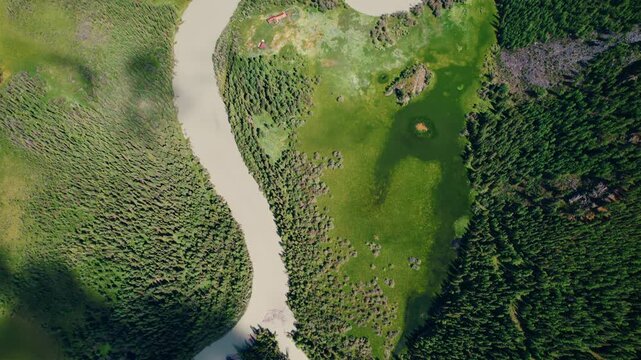 Aerial sweeping view of meandering river winding through forested valley Altai and rocky hills, tracking along sinuous river bends.