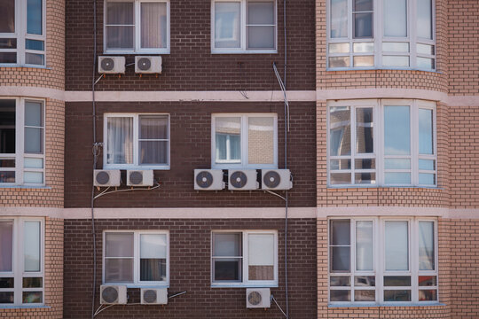 Modern brick residential building facade with multiple air conditioner units installed outside