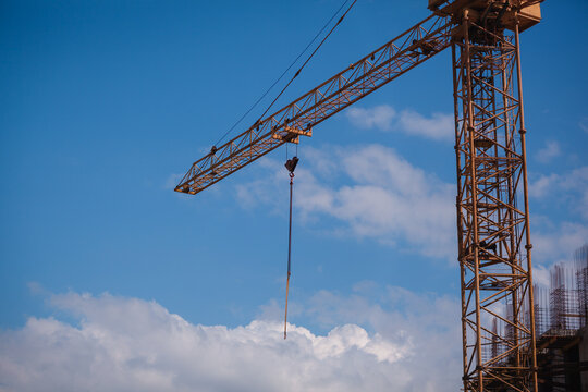 Close-up of a yellow tower crane jib end against clear blue sky with large copy space