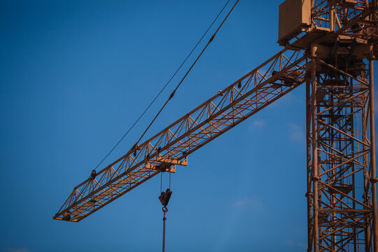 Close-up of a yellow tower crane jib end against clear blue sky with large copy space