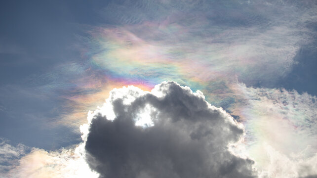 Rare cloud iridescence showing vibrant rainbow colors diffracting through high altitude wispy clouds