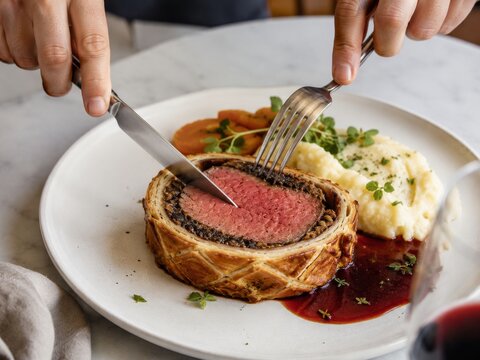 Disfrutar de un platillo de carne envuelta en masa con pur&eacute; y verduras en un restaurante
