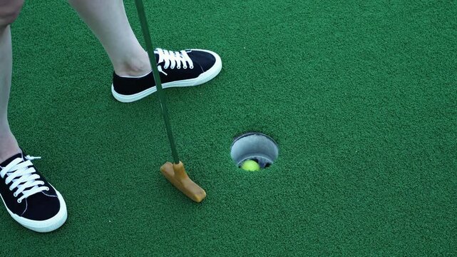 Horizontal 4K close-up video of a mini golf ball being putted into a hole, highlighting precision, sport, and recreational gameplay