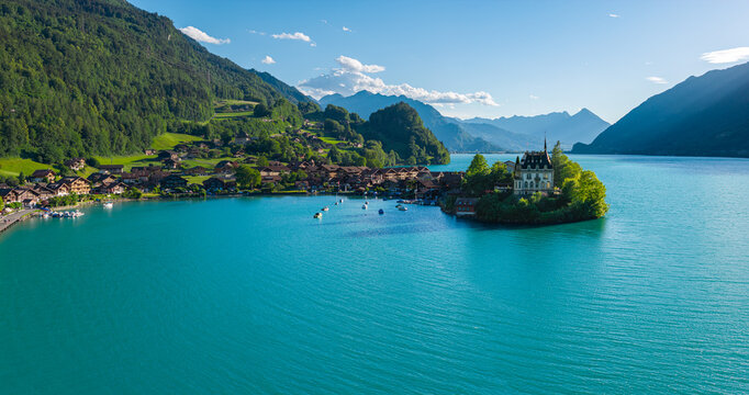 Aerial drone panorama of Iseltwald village and iconic Schloss Seeburg castle on the turquoise Lake Brienz in Switzerland.