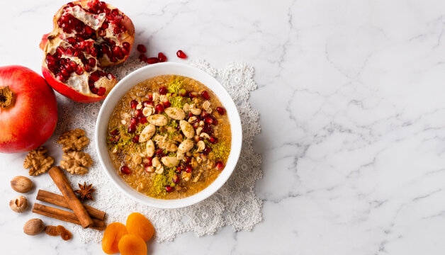 Traditional Turkish Ashure Dessert in White Porcelain Bowl on White Marble Background with Copy Space.