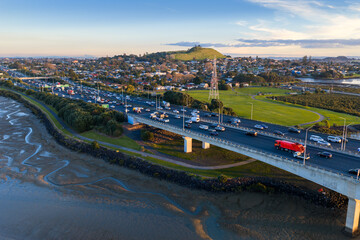 Obraz premium Aerial view of heavy traffic on the Mangere bridge in Auckland, New Zealand, during sunset. Commuters travel home as the sun sets over the city.