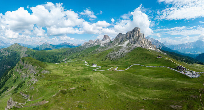 Aerial drone panorama of Passo Giau mountain pass in the Italian Dolomites. Winding alpine road and Ra Gusela peak surrounded by green meadows.